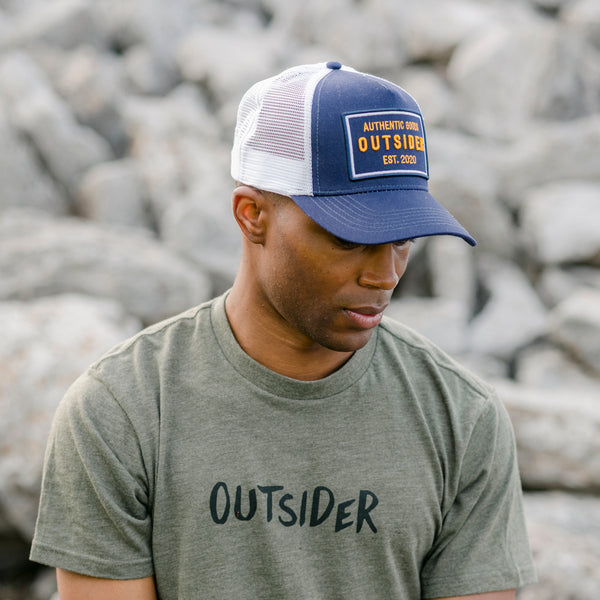 Outsider Authentic Goods Blue, White, and Yellow Adjustable Snapback Hat modeled on a man